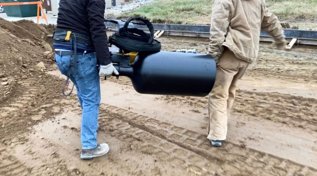 Curb Roller being lifted by two men